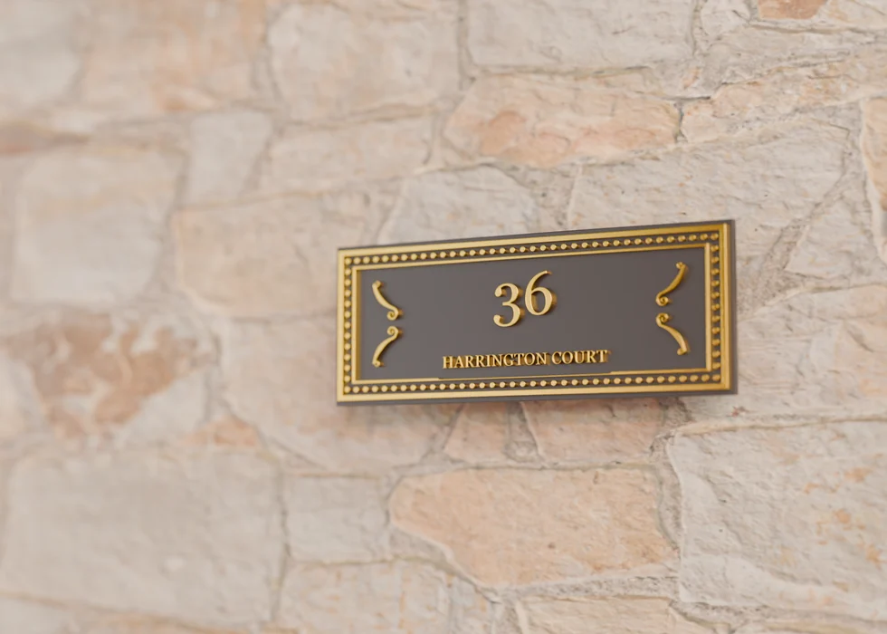 A Heritage Rectangle nameplate in black and brass on a stone entrance wall